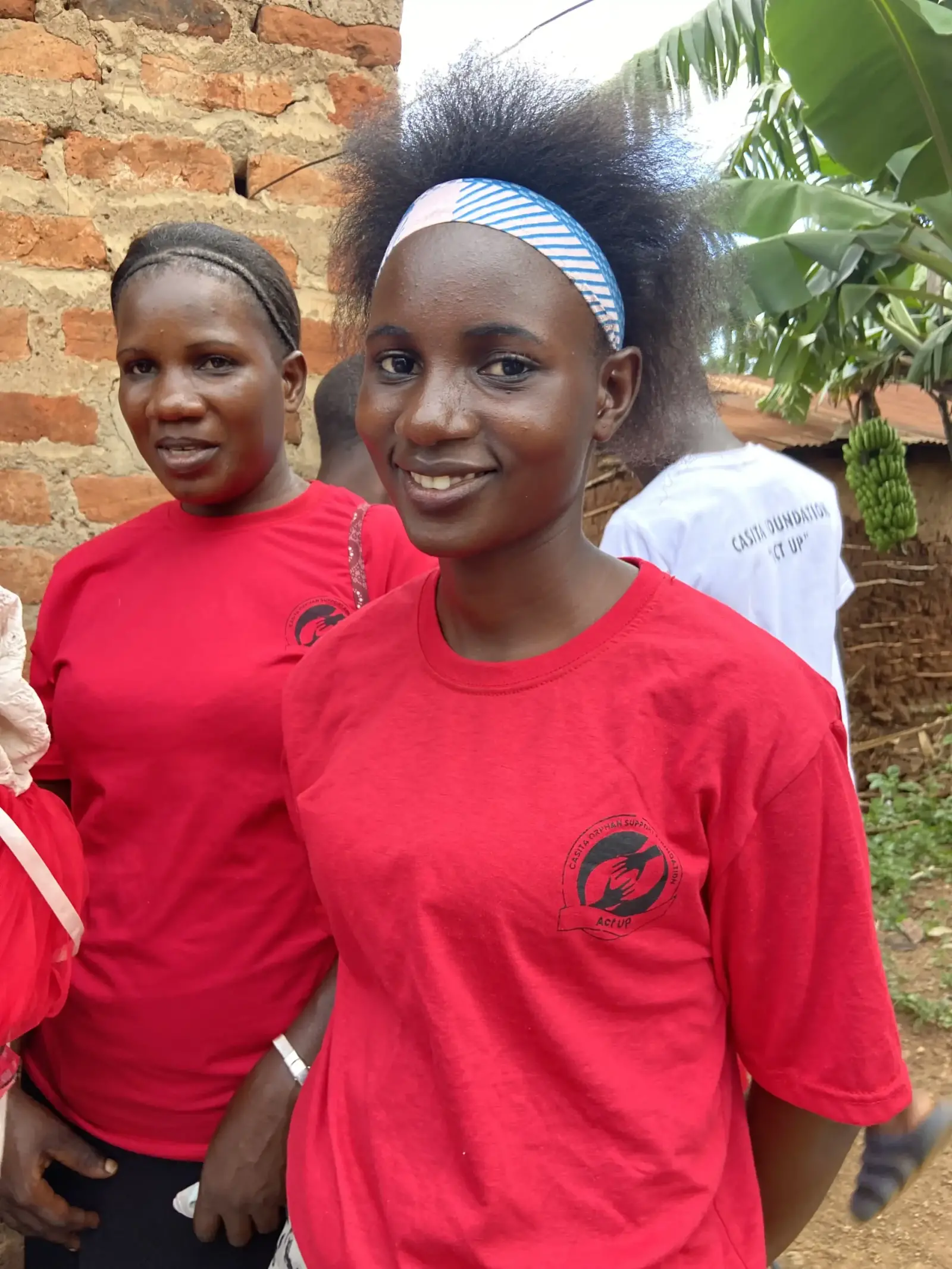 Two young women in Casita Orphans Foundation red shirts smiling